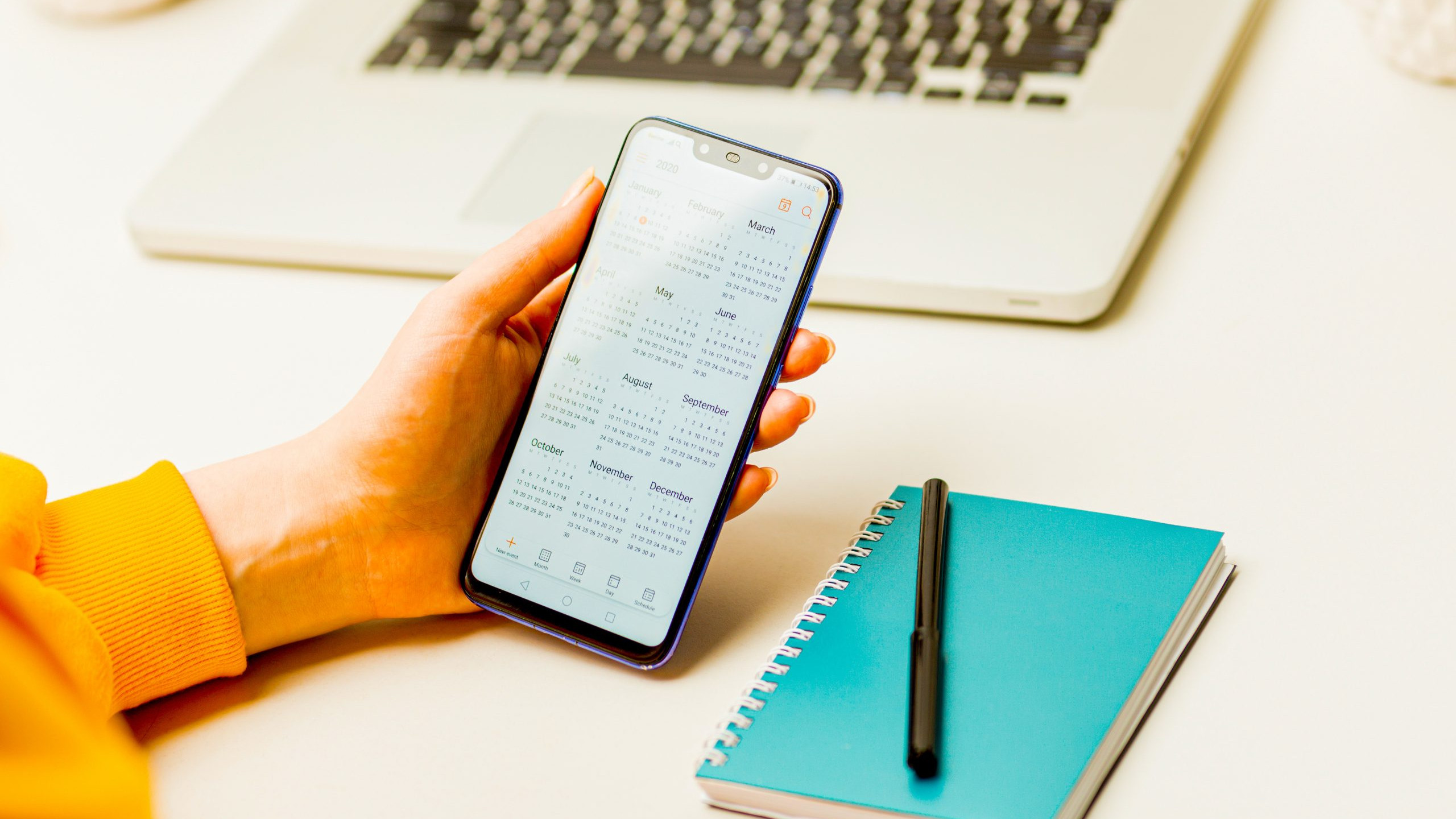 Woman holding phone and using calendar to make her plan in the notepad
